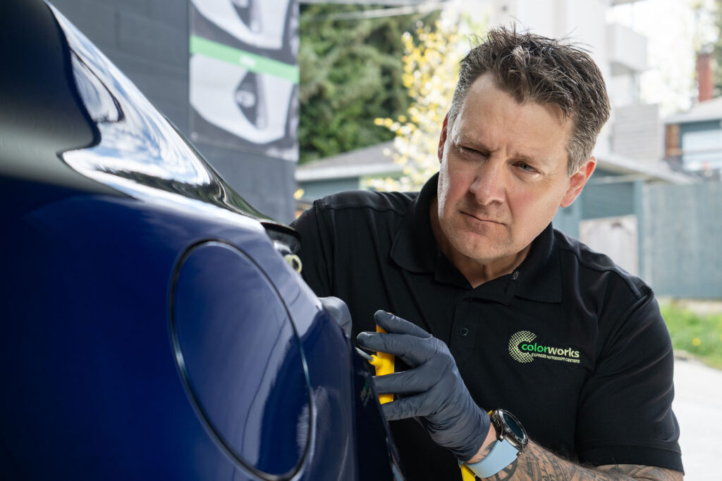 Technician performing dent repair on a vehicle at Colorworks.