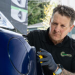Technician performing dent repair on a vehicle at Colorworks.