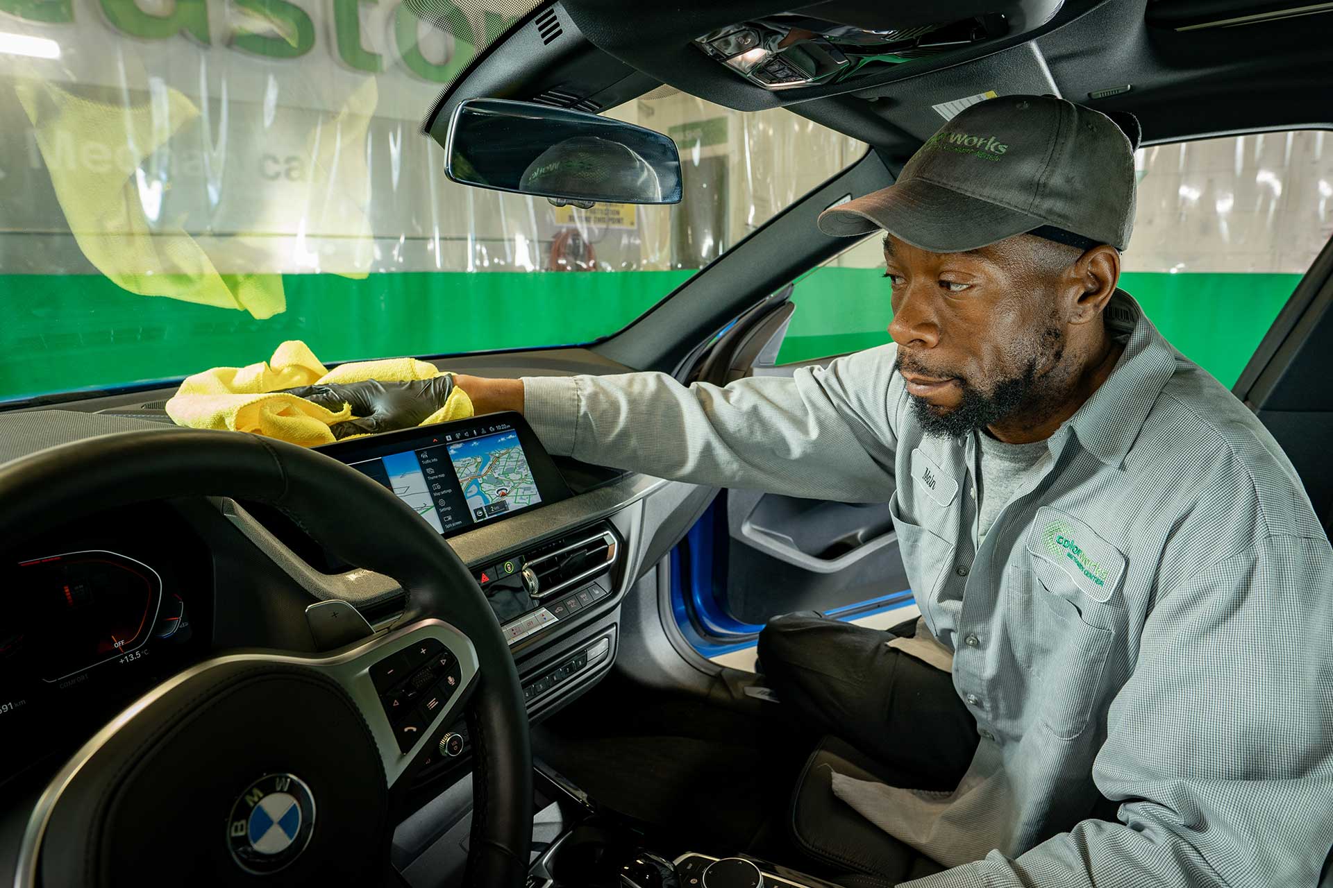 Technician cleaning vehicle interior during a detailing service.