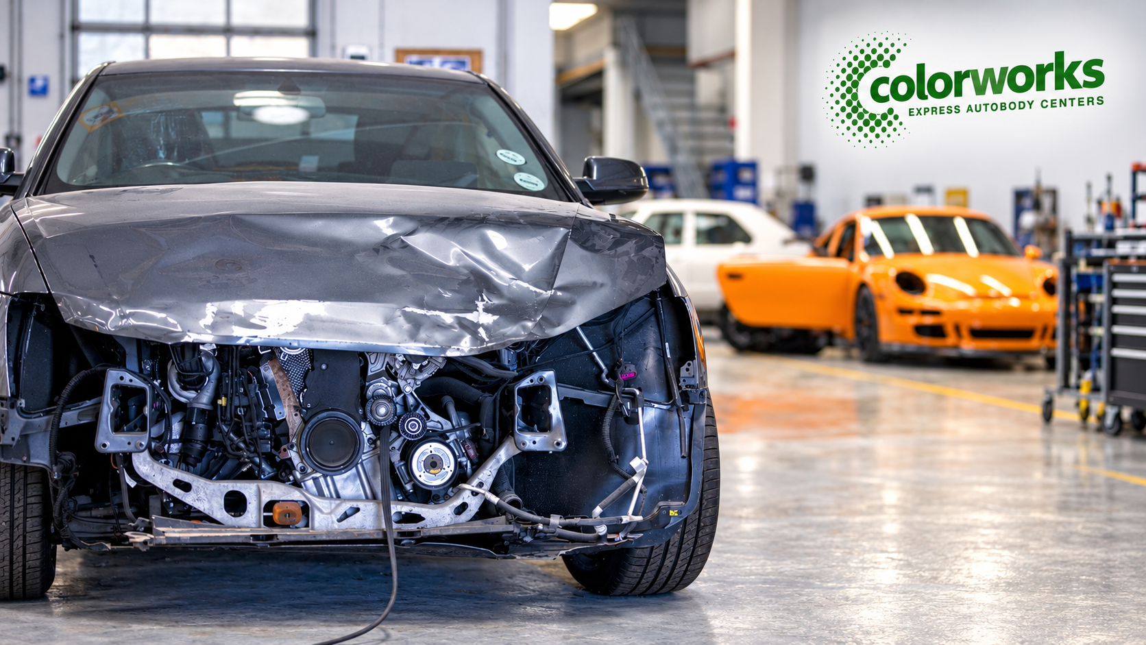 Damaged grey Land Rover in a collision repair workshop with Colorworks Express branding