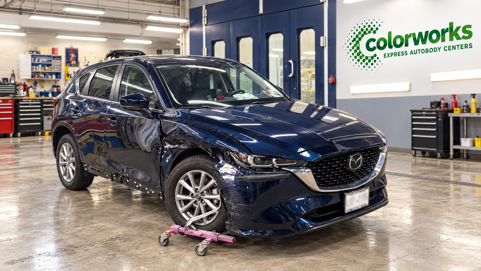 Dark blue Mazda CX-5 with collision damage in a body repair shop, with Colorworks Express branding