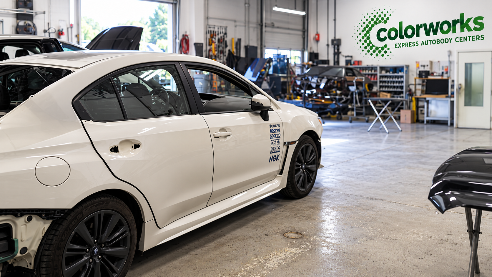 White Subaru sedan undergoing body repairs in a workshop, with Colorworks Express branding